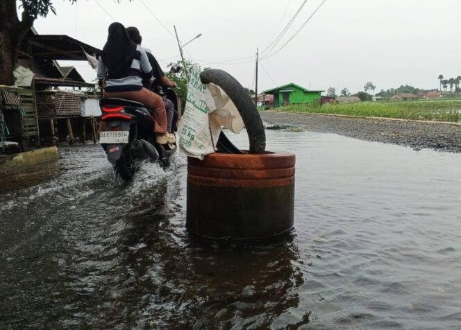 
 Jalan rusak berlobang dipasang drum di tengah banjir di Kampung Melayu Ilir, Martapura Timur, Kabupaten Banjar. foto-haris 