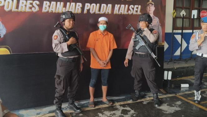 
 Tersangka A saat dikawal petugas dalam Press Conference di Polres Banjar Kalsel, Senin (22/12/2025). Foto: Ofal Ricek.ID 