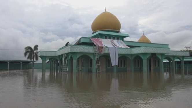 
 Terlihat seorang dari beberapa warga yang mengungsi di atap Masjid gegara banjir. foto: ricek.id